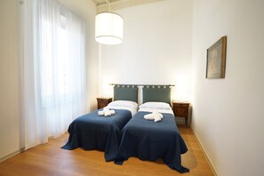A double bed room with two beds, a hanging light fixture, a bedside table, and a framed picture on the wall. - The emotion of living in a Renaissance palace in the heart of Florence (Firenze)