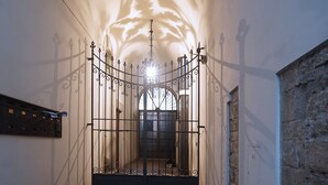 A narrow hallway with a metal gate at the end, leading to a brighter area. - The emotion of living in a Renaissance palace in the heart of Florence (Firenze)