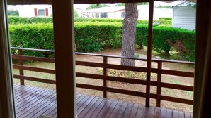 Una terraza de madera con vistas a un jardín cuidado y un árbol.