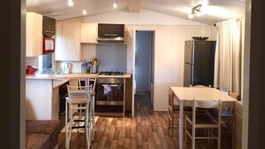 Una cocina compacta con comedor, piso de madera y vista al cuarto contiguo.