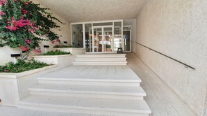 A set of white steps leading to a building entrance with glass doors and a metal handrail. - Blaumar B38 Estartit apartment rental with pool and air conditioning (Estartit)