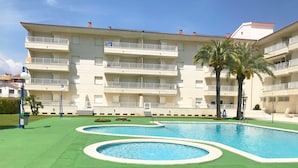 A multi-story hotel with a swimming pool area featuring two circular pools and a green lawn. - Blaumar B38 Estartit apartment rental with pool and air conditioning (Estartit)
