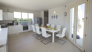 Una cocina moderna con armarios blancos, una mesa de comedor con sillas, un refrigerador y un microondas.