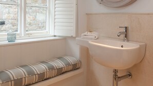 Une salle de bain avec une fenêtre, un lavabo et un miroir rond.