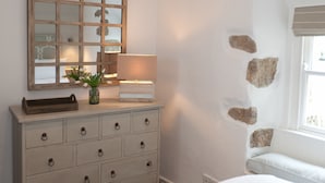 Une chambre à coucher avec une commode, un miroir, une lampe et une fenêtre donnant sur un beau paysage.