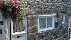 Un bâtiment en pierre avec une porte blanche et une fenêtre.