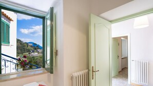 Een kamer met uitzicht op een bergachtig landschap door een raam met groene luiken.