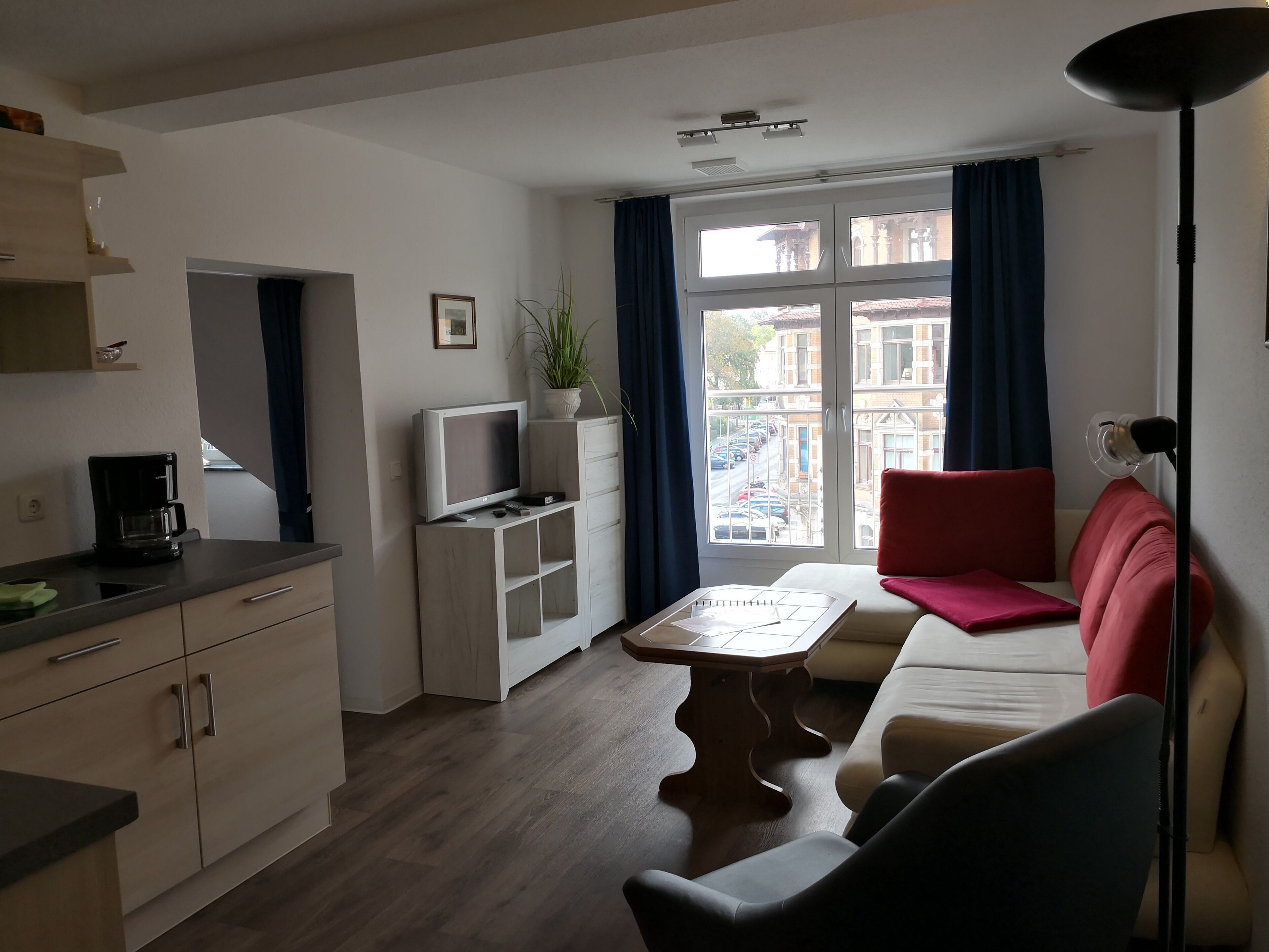 A modern living room with a sofa, a coffee table, a TV on a stand, and a dining table.