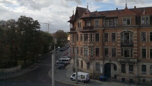 Vista de la calle con una fila de coches estacionados, una furgoneta blanca y un edificio de arquitectura ornamentada.