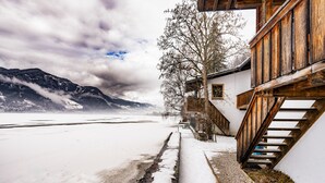 Eine verschneite Landschaft mit einer Holztreppe, die zu einem Gebäude mit einem Balkon führt.