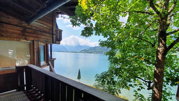 Eine Holzhütte mit einem Balkon mit Blick auf einen See und Berge.