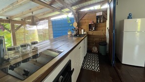 Ett kompakt kök med en bänkskiva i trä, en diskho och ett vitt kylskåp.