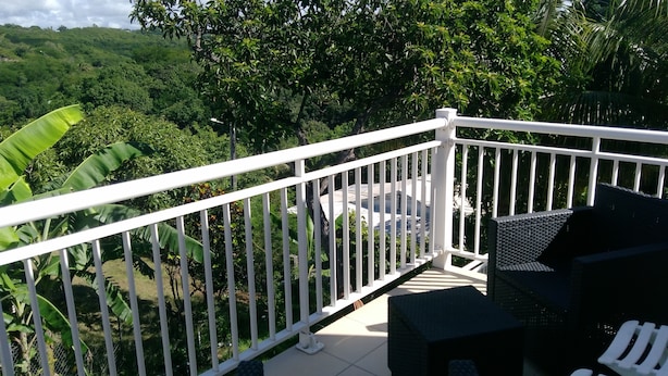 Ein Balkon mit weißen Geländern, der auf eine üppige, grüne Landschaft blickt.