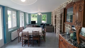 Comedor con mesa y sillas, televisor y vista al jardín.