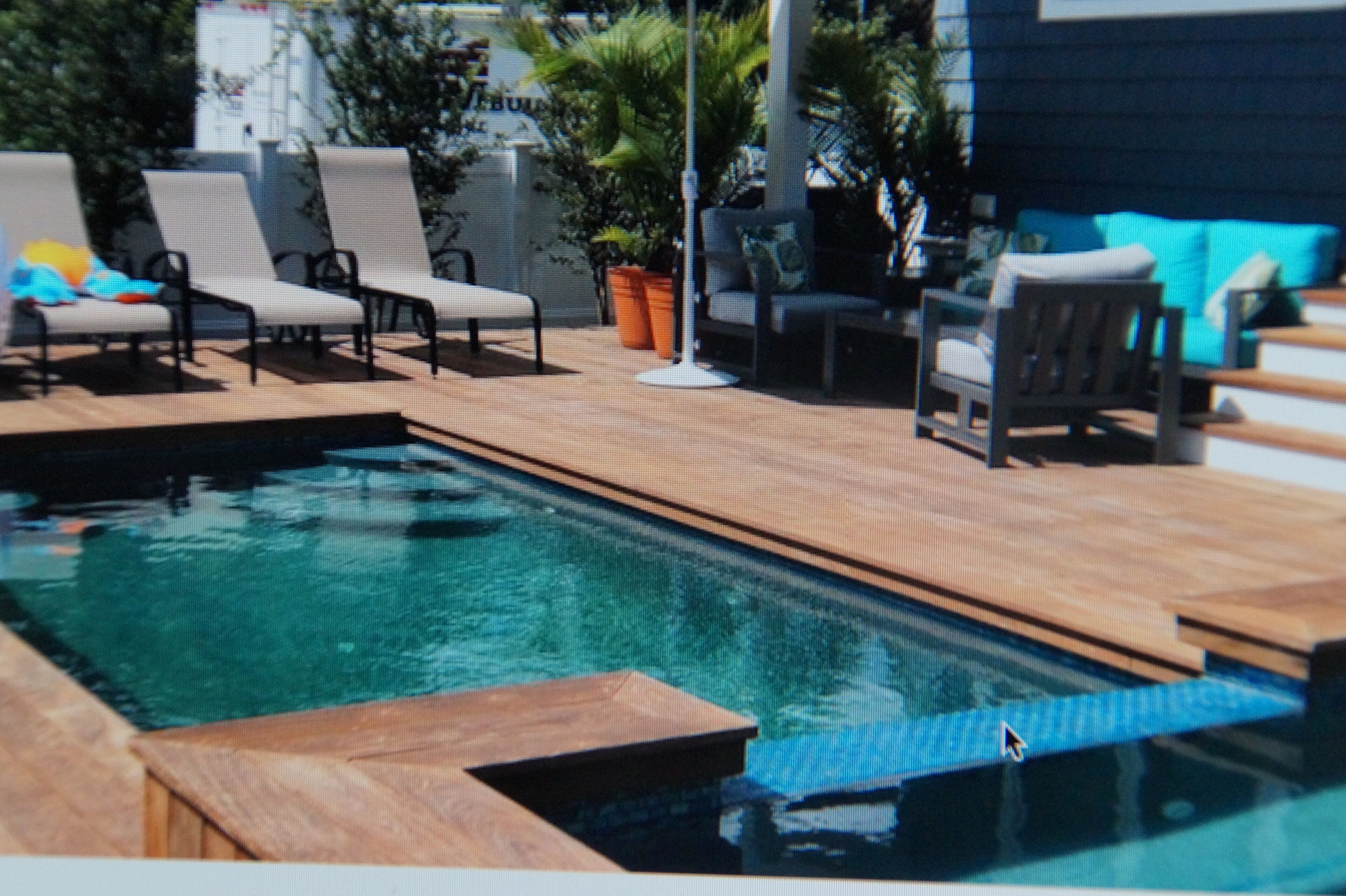 A swimming pool with lounge chairs and a wooden deck.