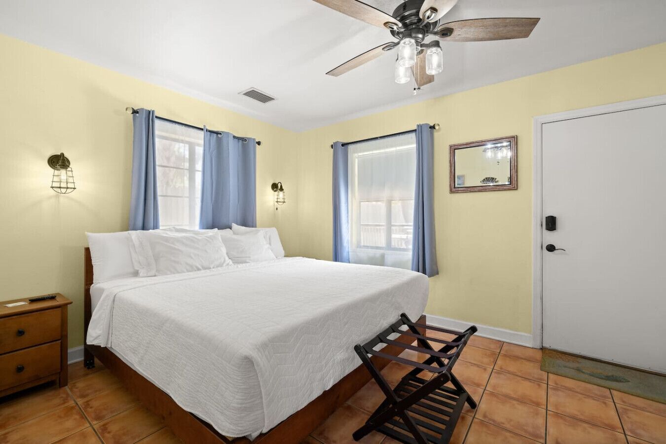 A bedroom with a bed, a nightstand, a ceiling fan, and a door.