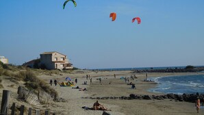 Une plage avec des gens, des tentes et un bâtiment.