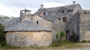 Un bâtiment en pierre doté de nombreuses cheminées et d’un toit traditionnel en pierre.