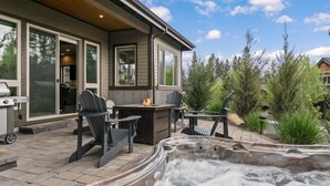Un patio con jacuzzi, mobiliario exterior y zona de parrilla.
