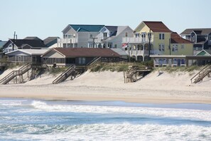 A beachfront property with multiple houses, some with balconies, and a sandy beach in the foreground. - "Personal Resort": Private Pool, Hot Tub, Ocean Views, Elevator, Walk to Town (Surf City)