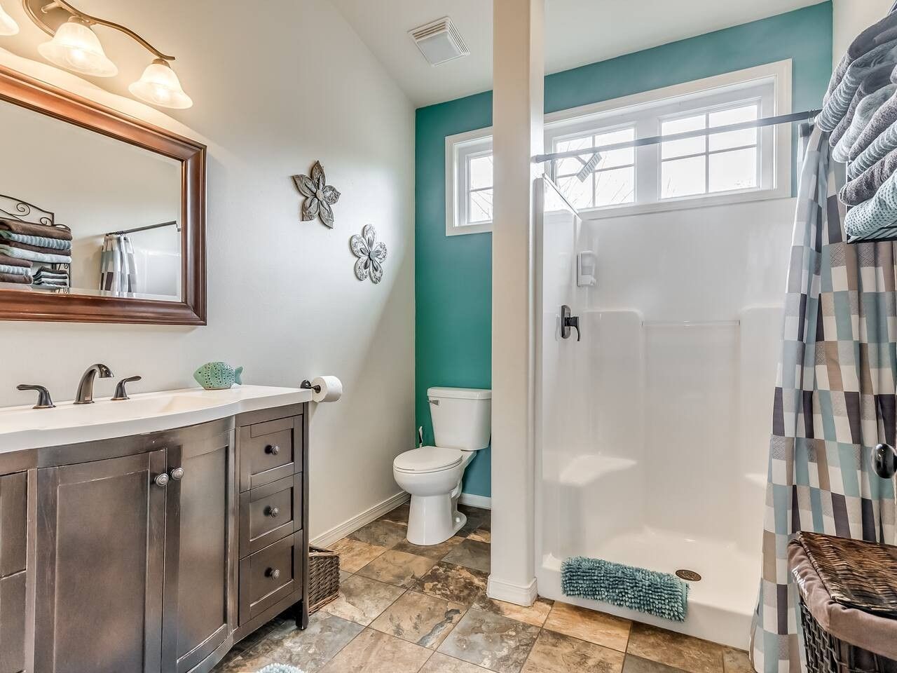 A bathroom with a white sink, dark cabinets, a white toilet, and a shower area.