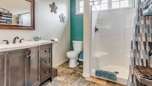Une salle de bain avec un lavabo blanc, des meubles sombres, des toilettes blanches et un espace douche.