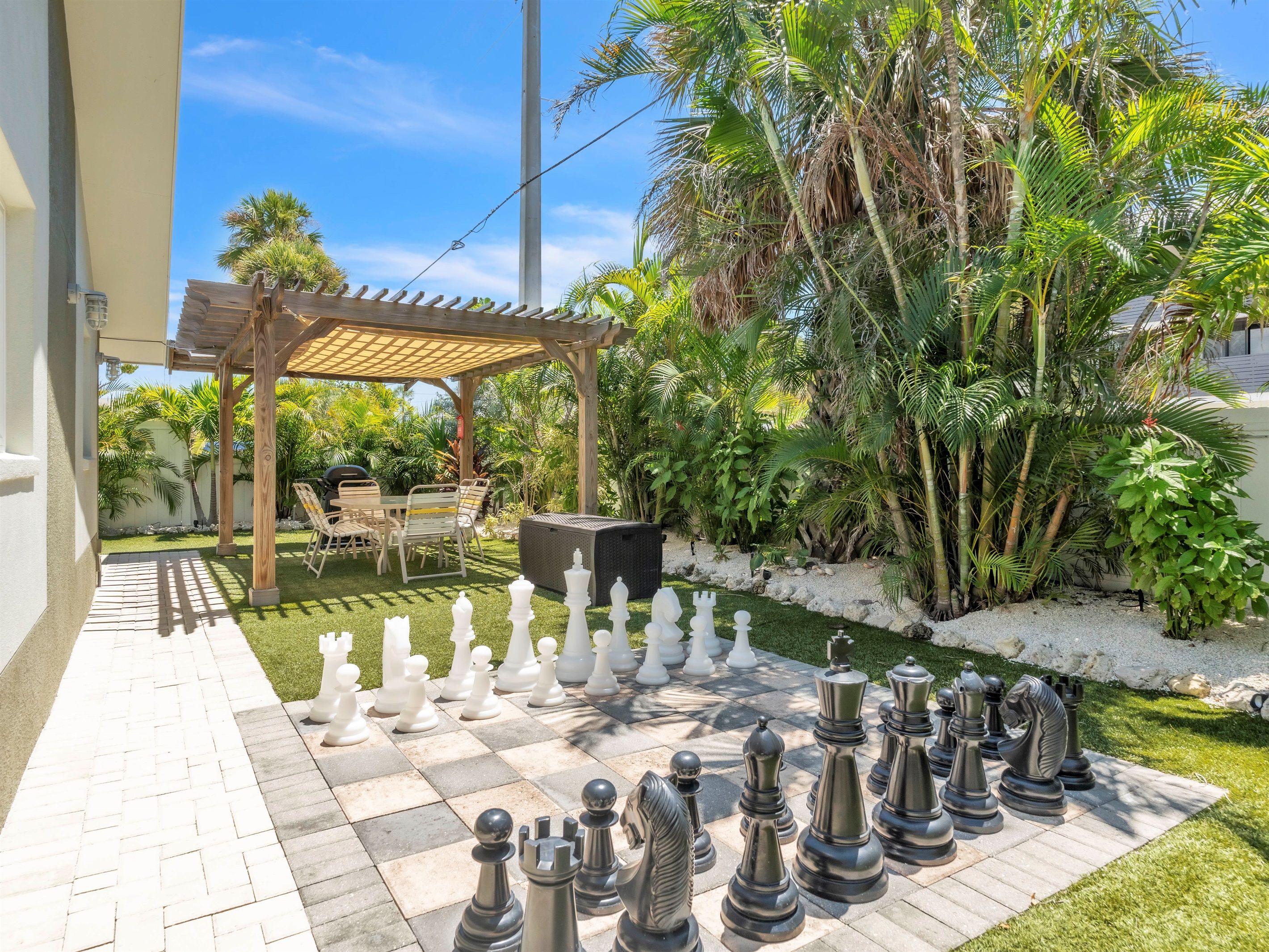 A chessboard set up outdoors with a pergola and patio furniture in the background.