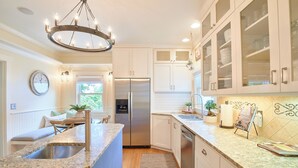 Een moderne keuken met een centraal eiland, roestvrijstalen apparatuur en witte kasten.