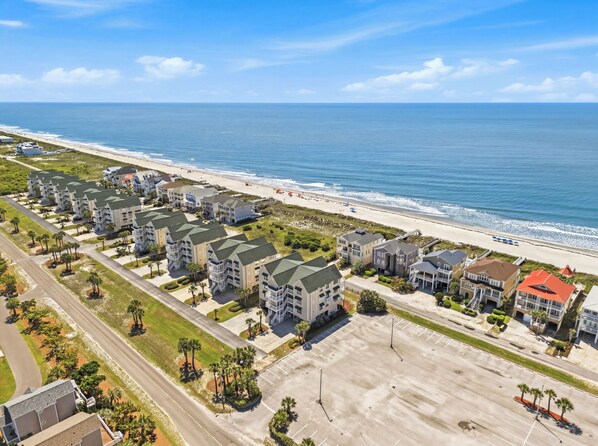 A coastal residential area with beachfront properties, a parking lot, and a clear view of the ocean.
