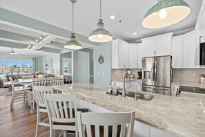 A modern kitchen with white cabinets, stainless steel appliances, and a marble island.