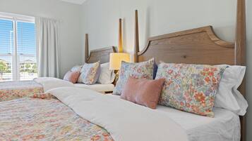 A double bed with floral bedding, a wooden headboard, and a bedside table with a lamp.