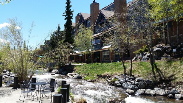 A riverside hotel with outdoor seating and a view of the river.