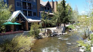 A riverside view with a restaurant named "TIKI MANIA" and a building with a ski resort sign.