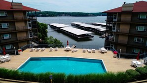 Un hotel con piscina, mobiliario exterior y vistas a un lago.