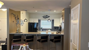 Una cocina moderna con una isla central, taburetes de bar e iluminación colgante.