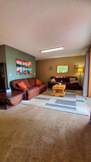 A living room with two sofas, a coffee table, a painting, and a lamp.