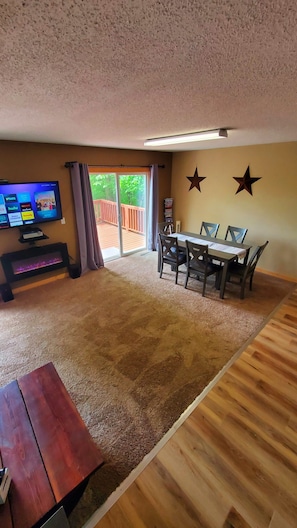 A living room with a TV, fireplace, dining table, and chairs.