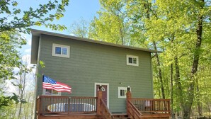 A two-story cabin with a front deck and a small staircase leading to the entrance. - Escape to Tranquility on Ross Lake: A Perfect Getaway! (Aitkin)