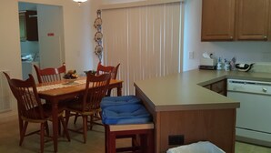 A dining area with a wooden table, chairs, and a blue cushioned bench. - Tranquil Lakefront Setting near Clemson SC with Private, Covered Dock (Seneca)