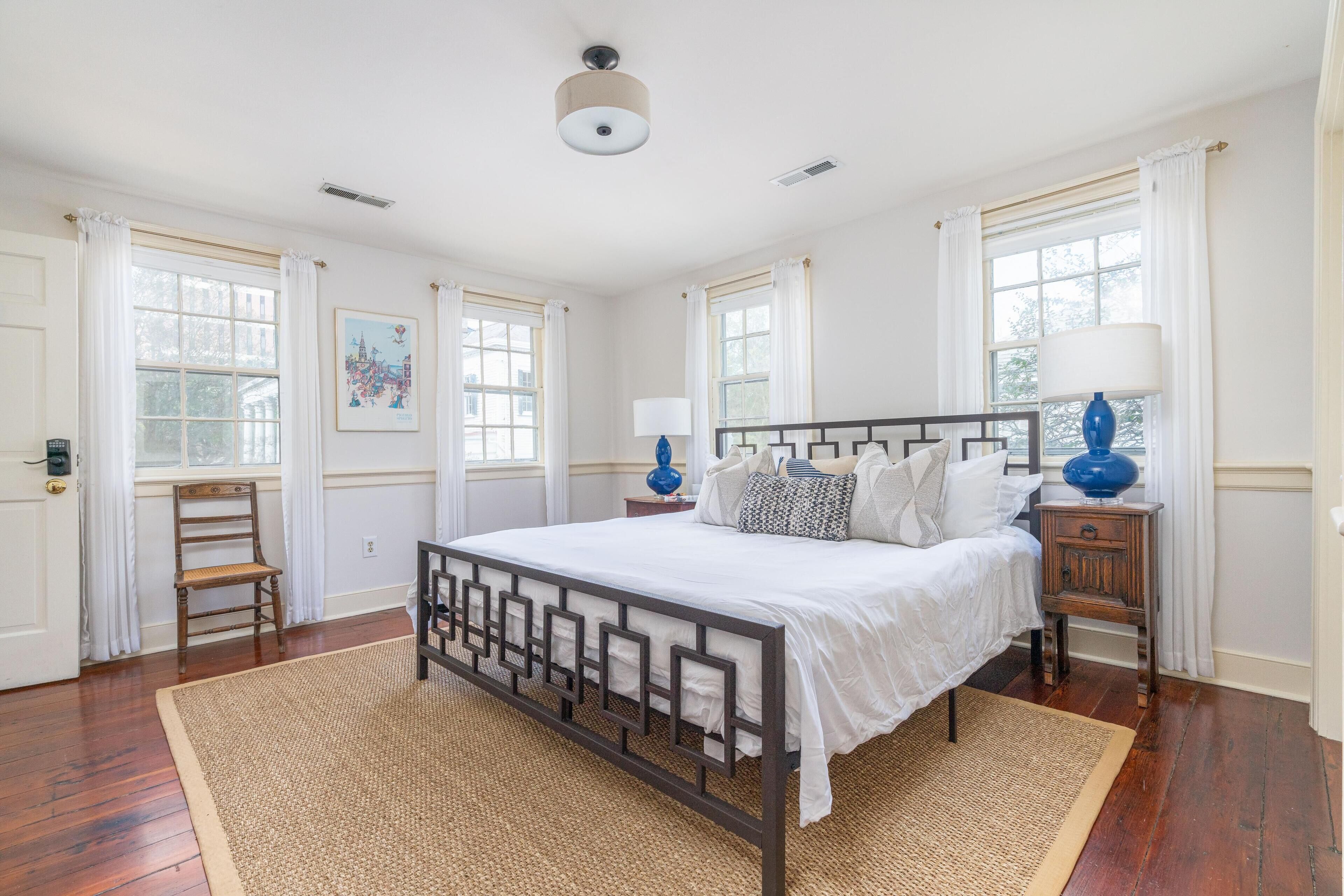 A bedroom with a wooden bed frame, white bedding, and two bedside tables with lamps.
