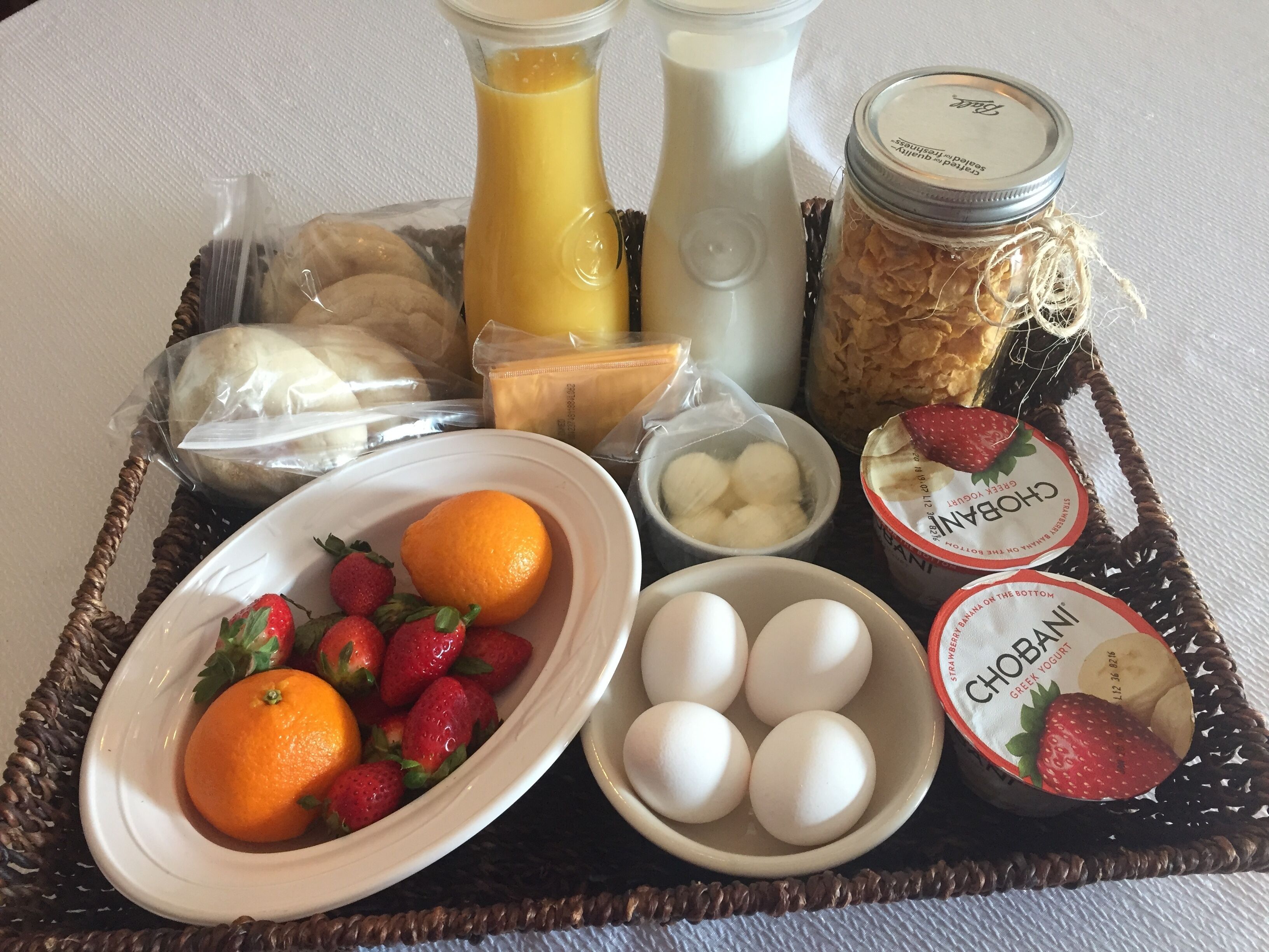 Un plateau de petit-déjeuner contenant divers aliments, notamment des fraises, des oranges, des œufs et du yaourt grec.