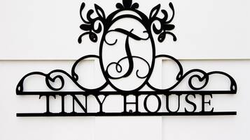 Een metalen bord met de tekst 'TINY HOUSE' en een decoratief ontwerp erboven.