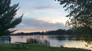 Zona de pícnic a la vora d'un llac, amb una banca i una vara de pesca.