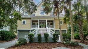 A two-story house with a front porch, a covered front entrance, and a small front yard with trimmed bushes and a palm tree. - Fabulous 4 BR/3.5 BA w/ Golf Views! Close to Beach! Amenity access included! No Pets Allowed. (Seabrook Island)