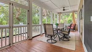 A covered porch with a table and chairs, a ceiling fan, and a view of greenery. - Fabulous 4 BR/3.5 BA w/ Golf Views! Close to Beach! Amenity access included! No Pets Allowed. (Seabrook Island)