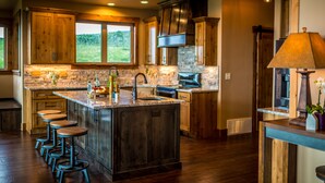 Una cocina amplia con armarios de madera, una isla grande con taburetes y vistas al exterior.