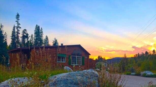A rustic cabin with a single window and a chimney, surrounded by tall trees and a clear sky. - Quiet Retreat with private courtyard In Grand Lake Village! (Grand Lake)
