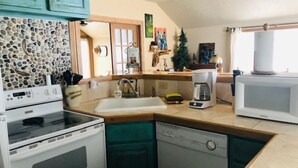A kitchen with a stove, dishwasher, and a coffee maker. - Quiet Retreat with private courtyard In Grand Lake Village! (Grand Lake)