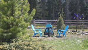 A wooden fence, a small tree, and three blue chairs in a natural setting. - Quiet Retreat with private courtyard In Grand Lake Village! (Grand Lake)