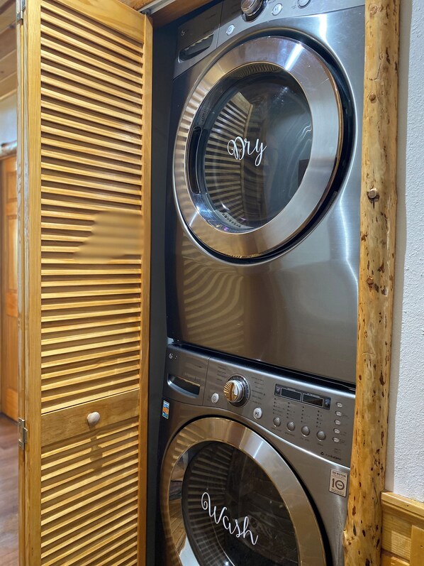 Un appareil combiné lave-linge et sèche-linge, de type « superposé », doté d’un panneau décoratif en bois.